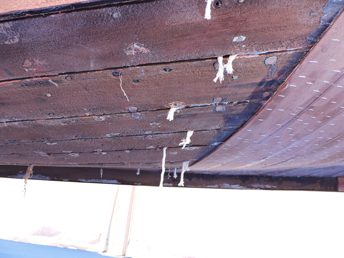 Coton de calfatage visible dans les coutures d’une coque de bateau en bois